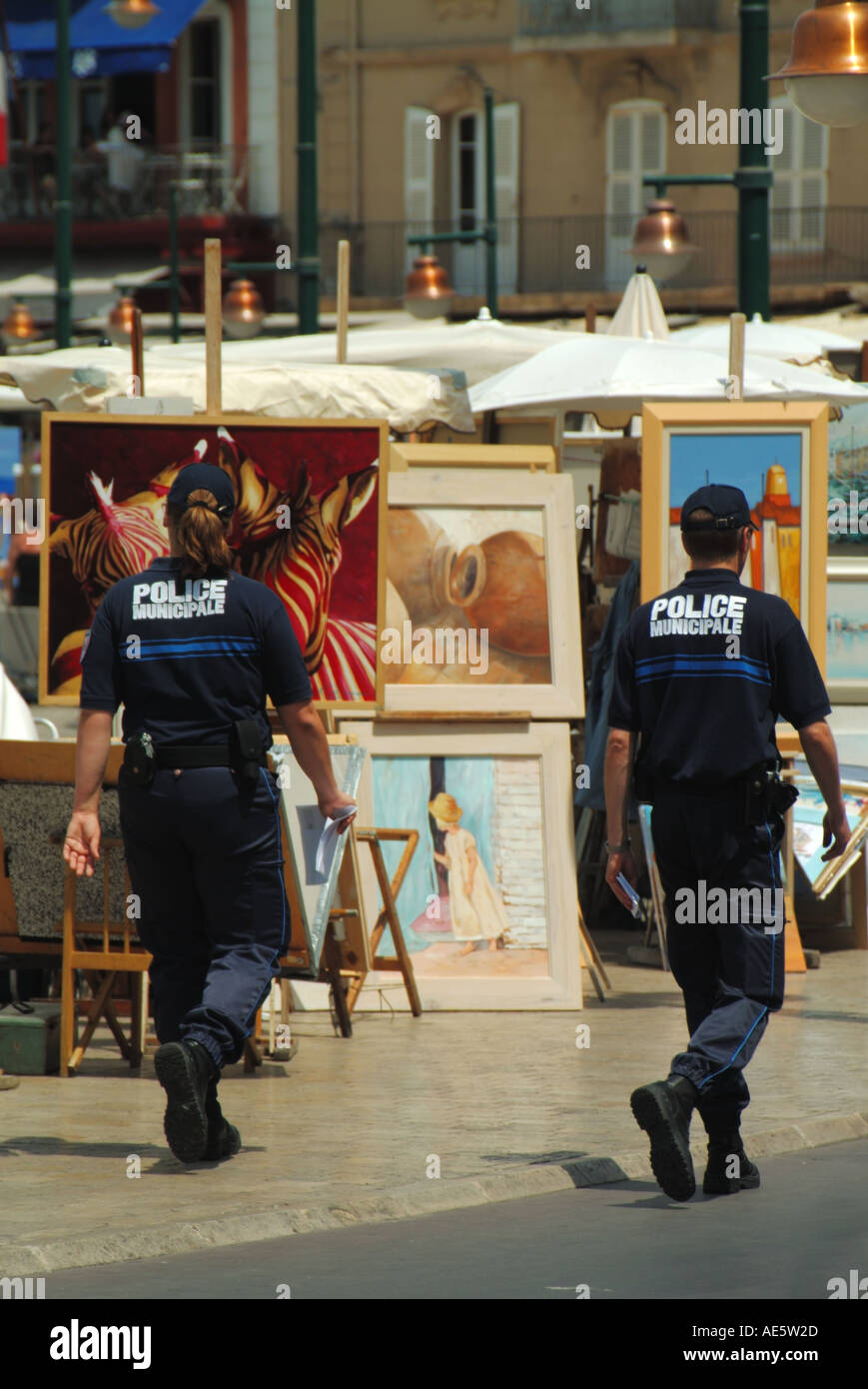 St Tropez waterfront street scene la gendarmeria francese a piedi accanto ad artisti mostra di Dipinti in vendita Cote d Azur Riviera francese nel Sud della Francia Foto Stock