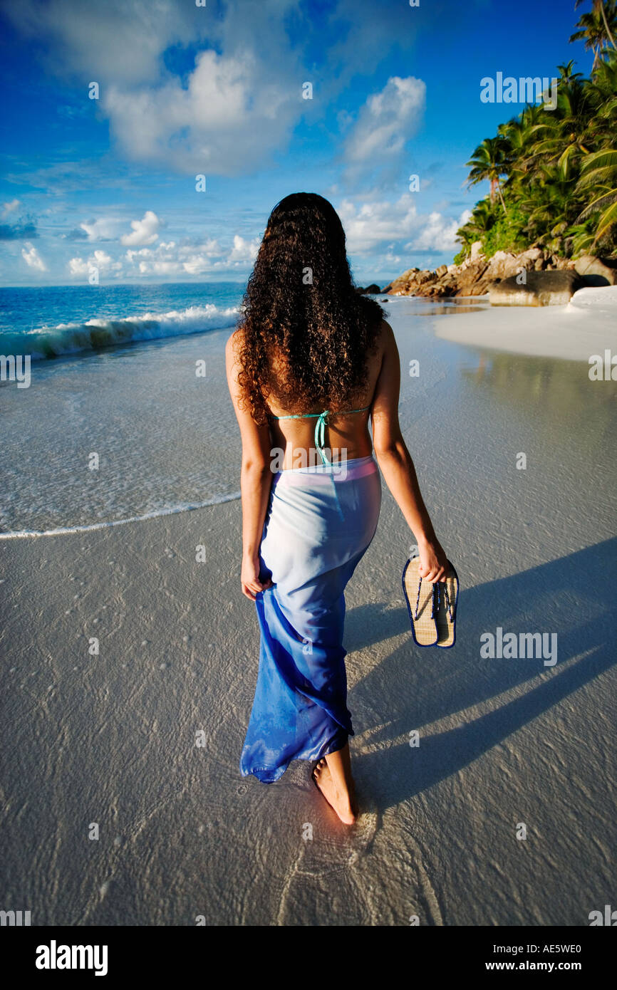 Donna che cammina sulla spiaggia di Anse Victorin spiaggia e palme Fregate Island Seychelles Foto Stock