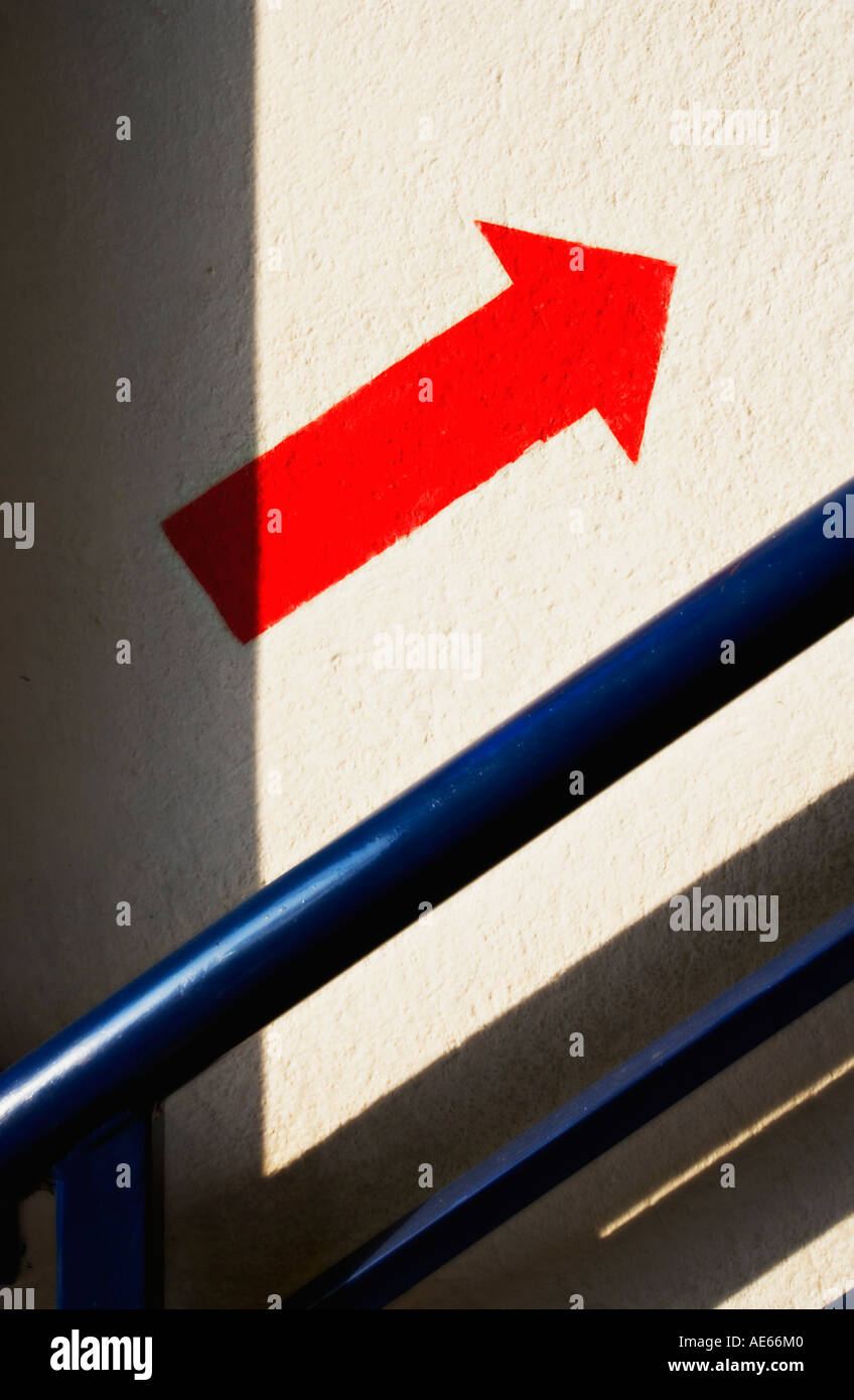 Freccia rossa in un modo segno dipinto sulla parete accanto a Scala Foto Stock
