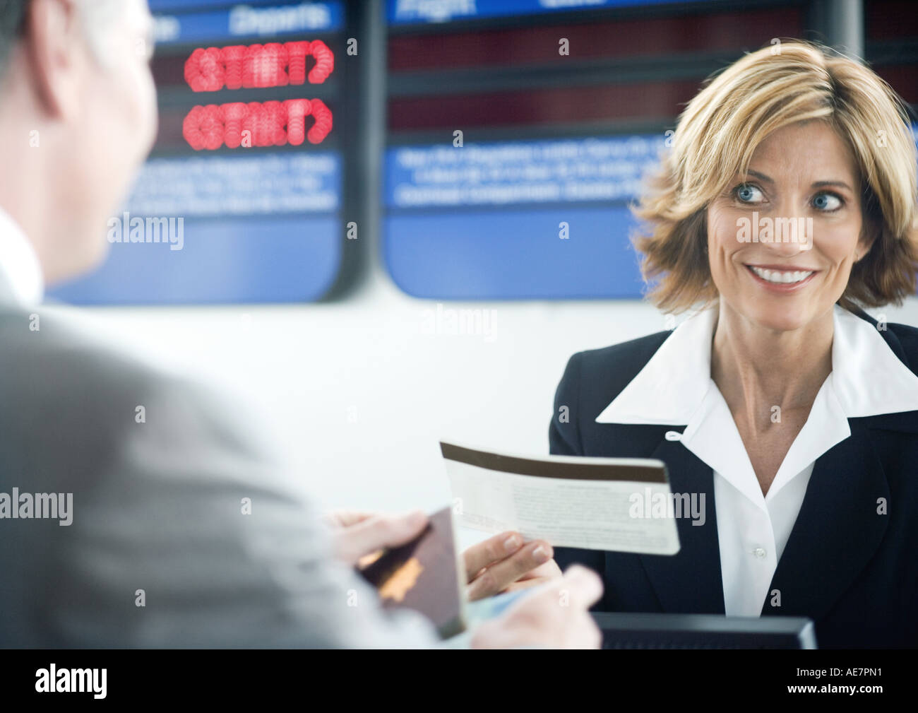 Compagnia aerea attendant consegna biglietto del passeggero al banco del check-in Foto Stock