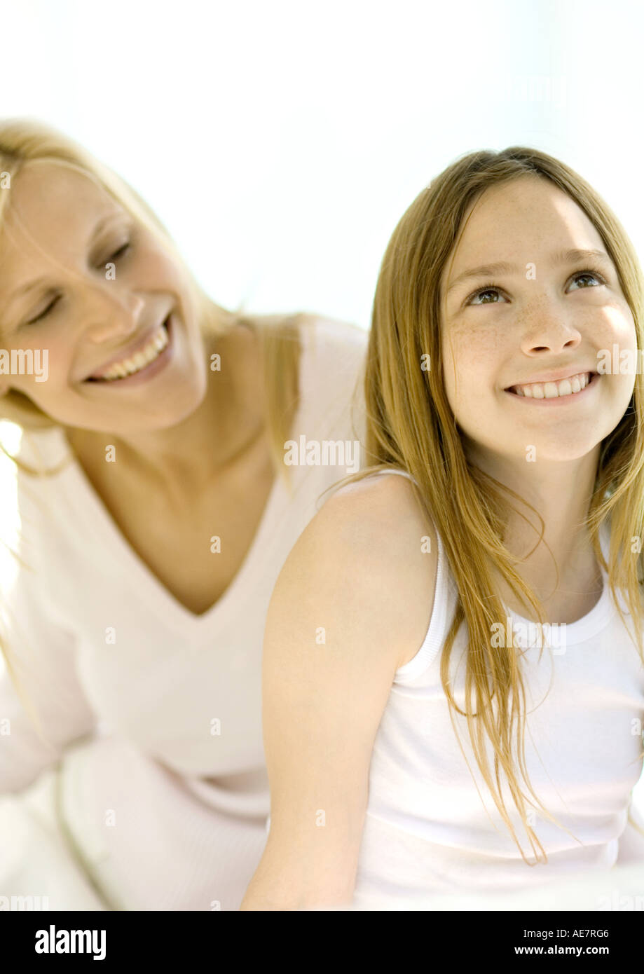 Ragazza sorridente e guardando in alto, madre guardandosi le spalle Foto Stock