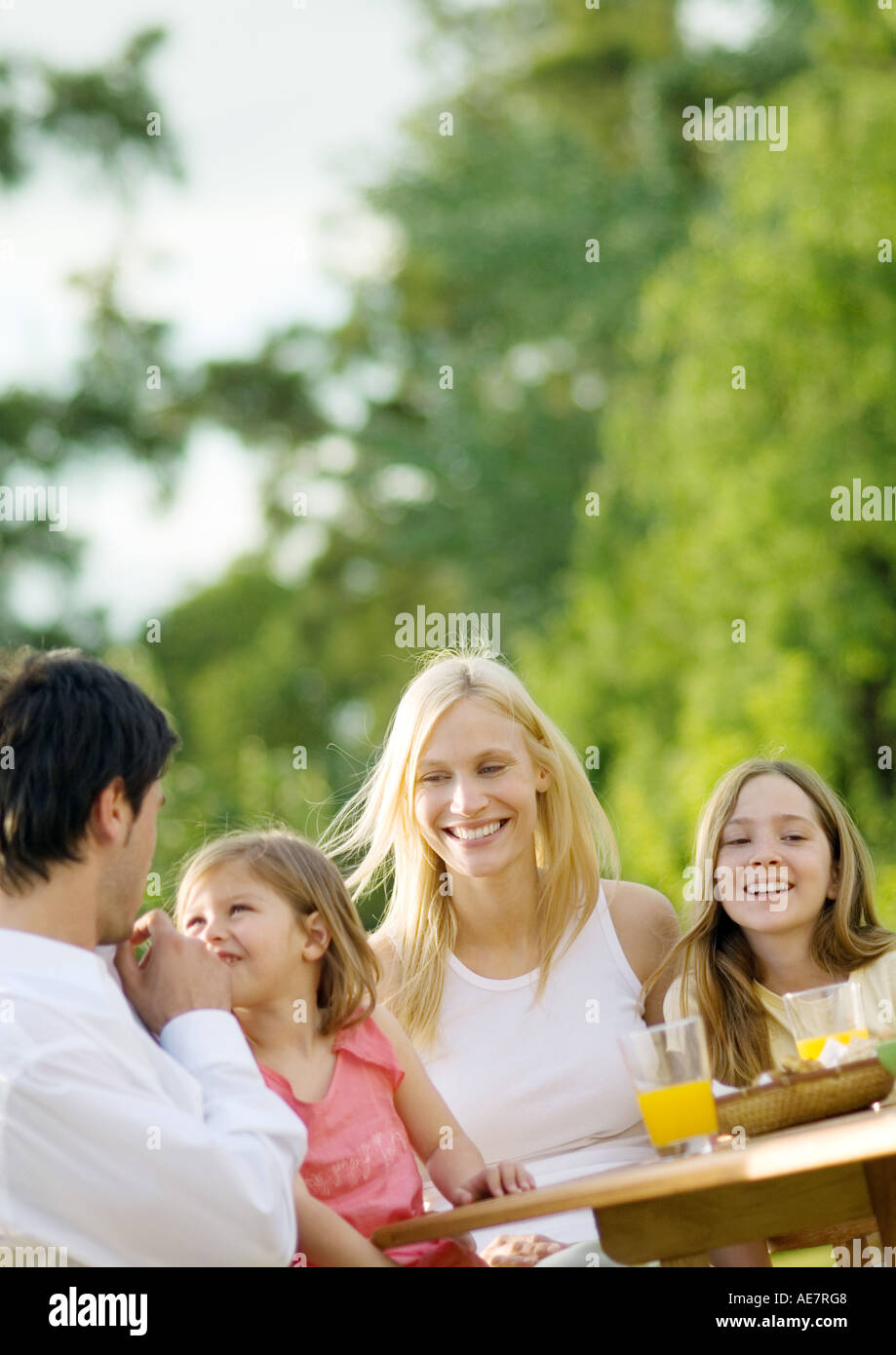 La famiglia seduta a tavola al di fuori Foto Stock