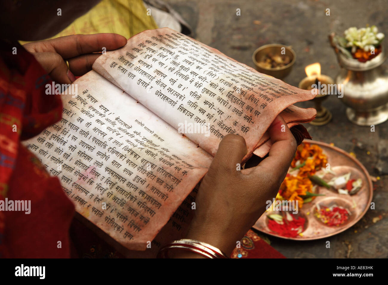 Donna indù dalla lettura delle sacre scritture durante la puja cerimonia di culto Foto Stock