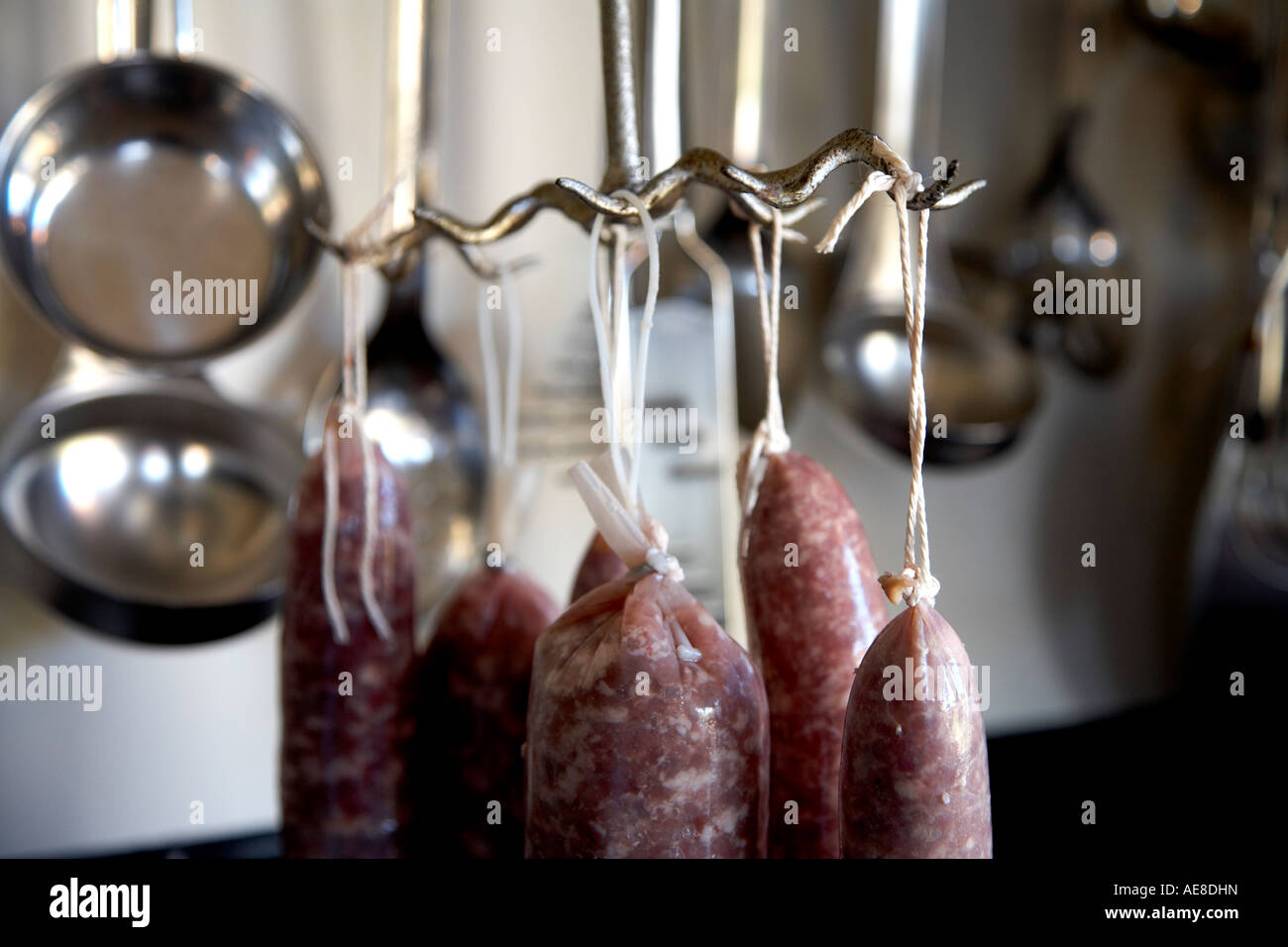 Home realizzato salami appesi su vecchi macellai tradizionali ganci Foto Stock