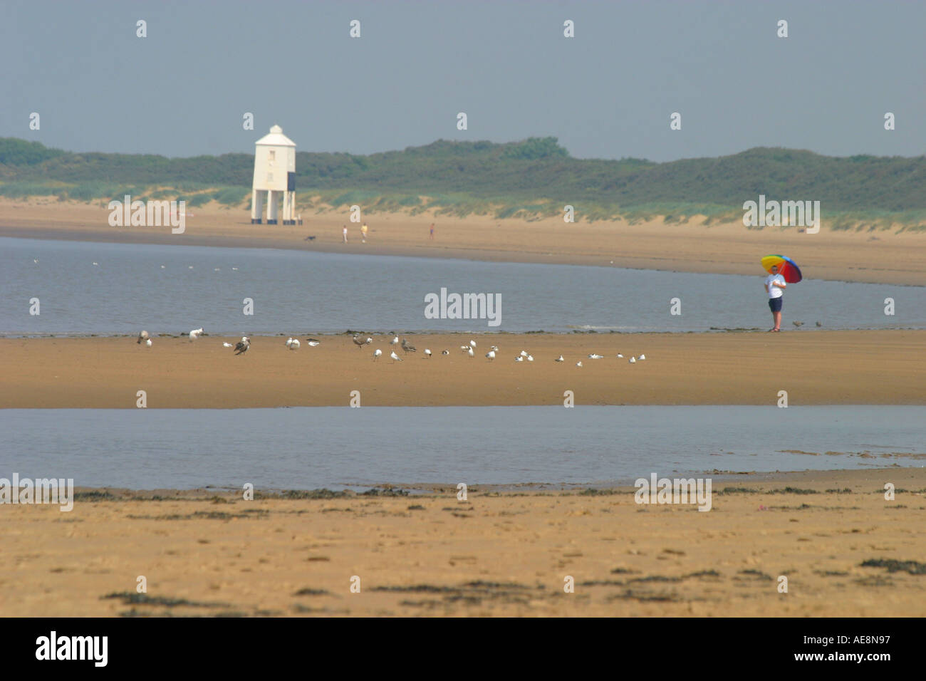 Burnham on sea beach e il faro uomo con ombrellone in primo piano Foto Stock