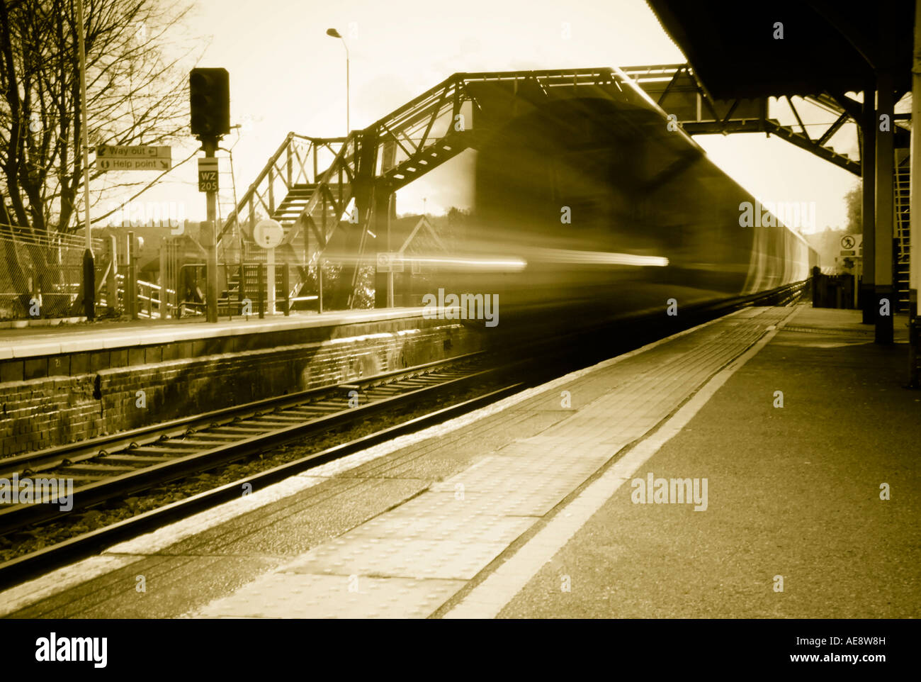 Accelerando il treno alla piccola stazione ferroviaria platform Foto Stock