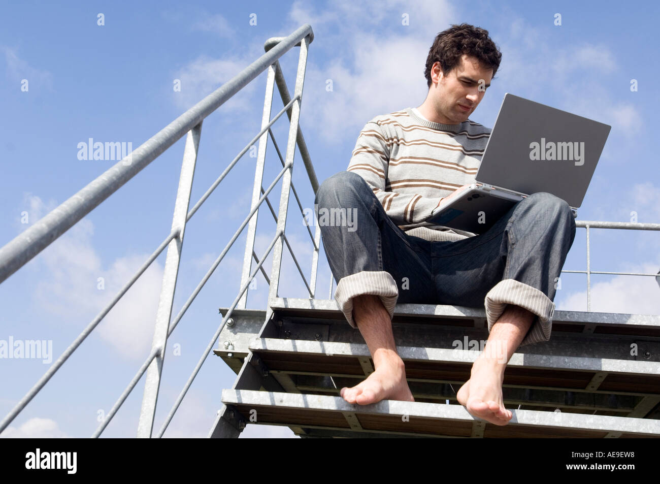 Uomo seduto sulle scale, utilizzando laptop, all'aperto, angolo basso Foto Stock