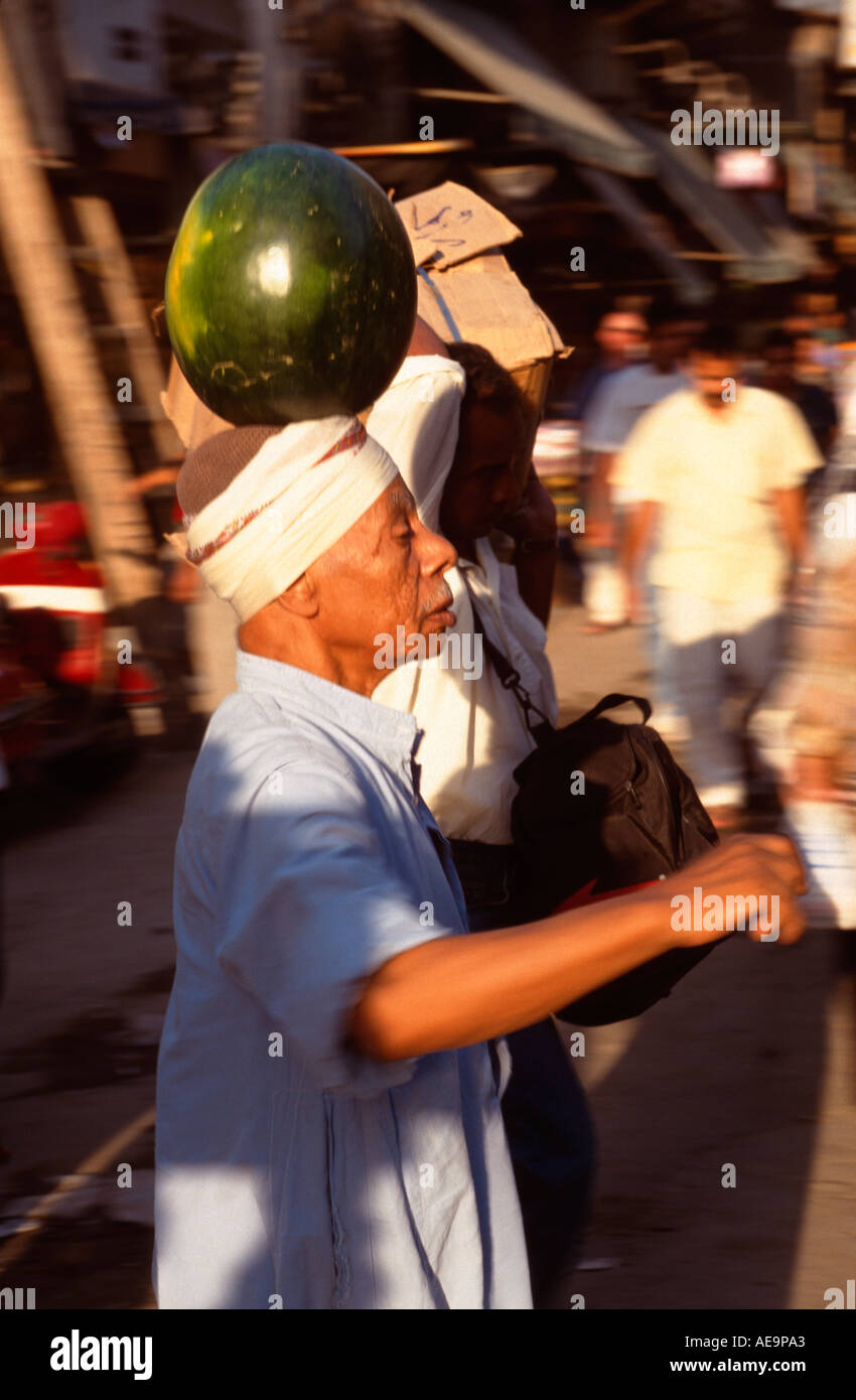 Il vecchio uomo che cammina attraverso il Bazaar di Khan el Khalili con un cocomero equilibrato sul suo capo, il Cairo, Egitto Foto Stock