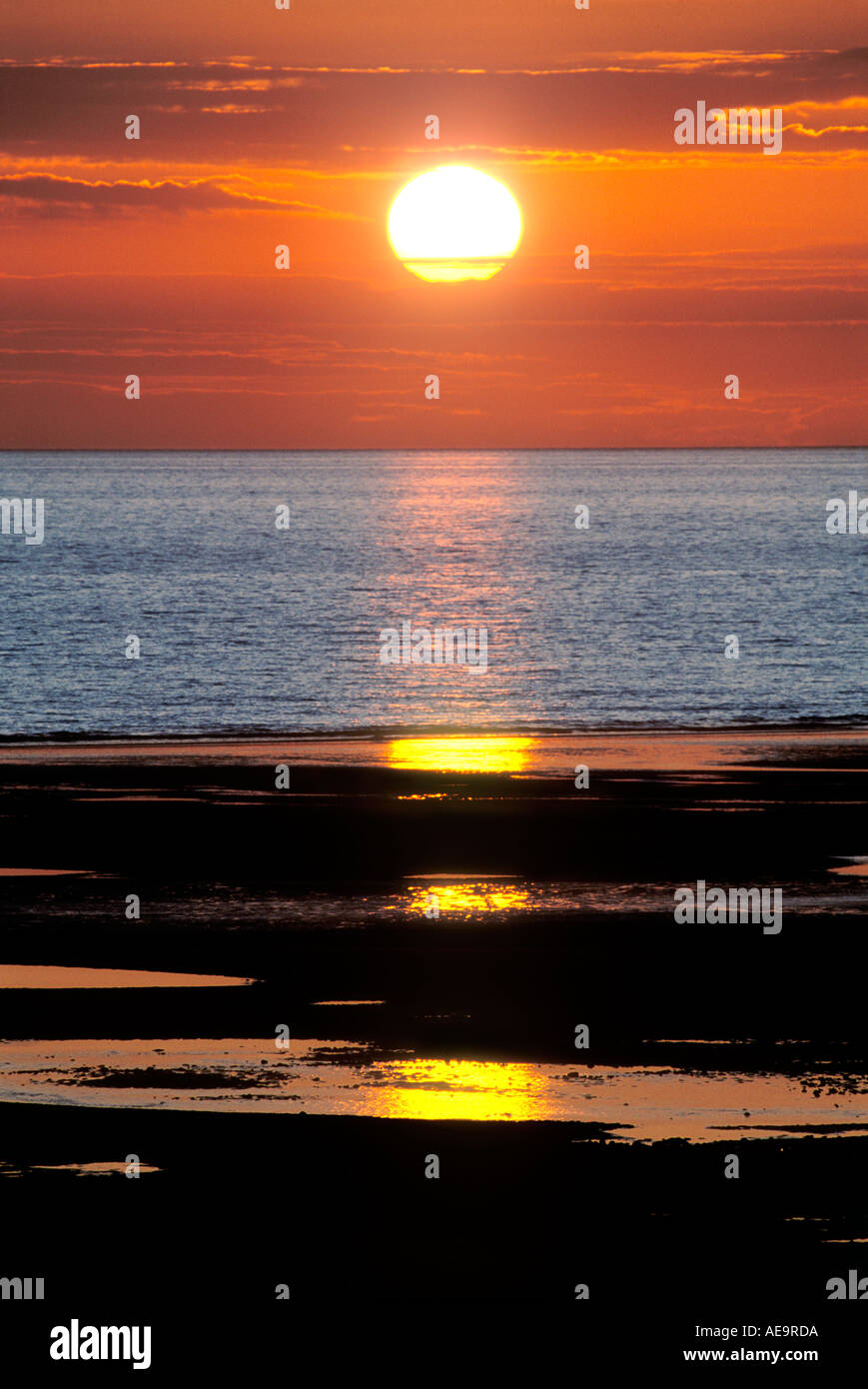 Drammatico tramonto sul mare e sulla spiaggia con riflessioni Foto Stock