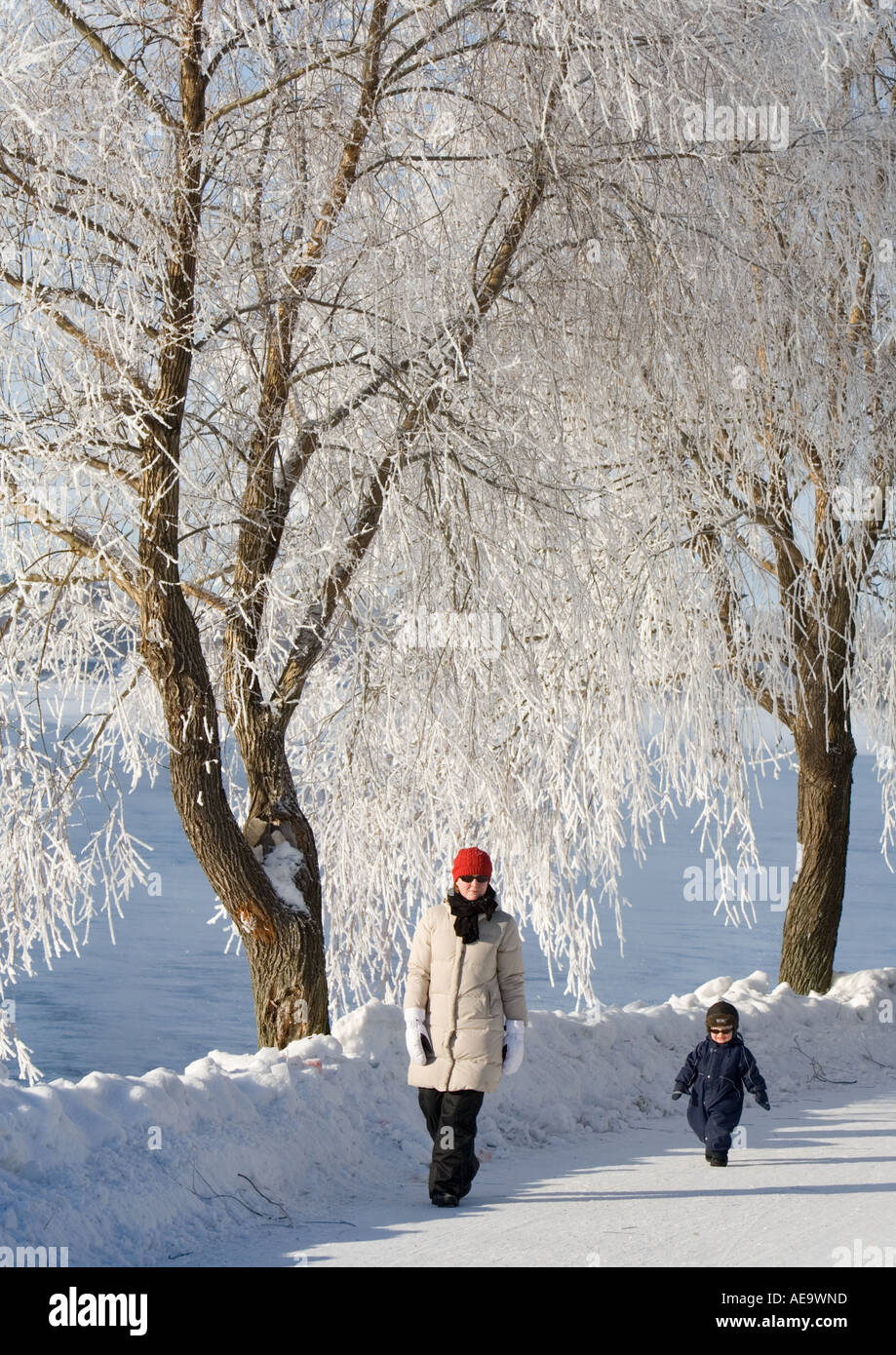 La madre e il bambino piccolo a piedi al di fuori il freddo inverno il giorno sotto il pupazzo di neve alberi , Oulu FINLANDIA Foto Stock