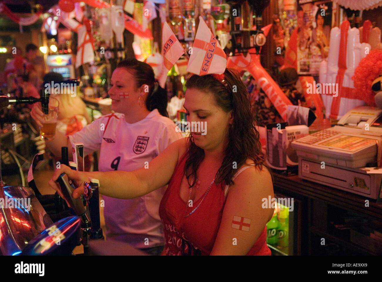 Emozionante partita di calcio della Coppa del mondo 2006. Le donne che tirano pinte di birra all'interno del pub sono decorate con bandiere inglesi che celebrano HOMER SYKES degli anni '2000 Foto Stock