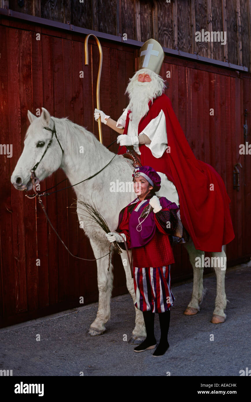 SAINT NICHOLAS montato su un cavallo bianco con un buffone Foto Stock