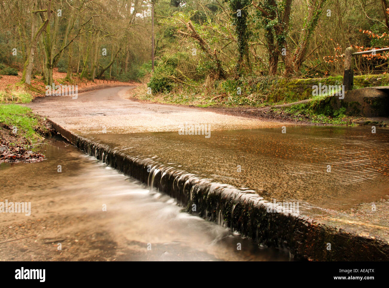 Una piccola cascata a partire da un flusso di fiume attraversando una strada. Foto Stock