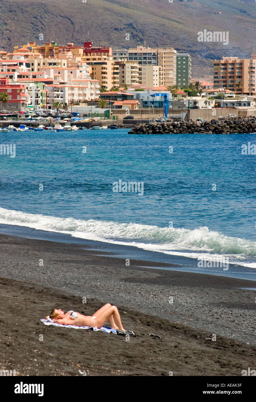 La donna a prendere il sole sulla spiaggia vulcanica Candelaria Tenerife Canarie Spagna Foto Stock