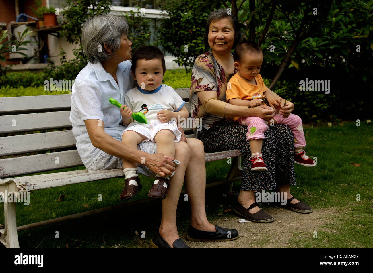 Donne anziane tenere i bambini in una comunità di Shanghai in Cina il 18 giugno 2006 Foto Stock