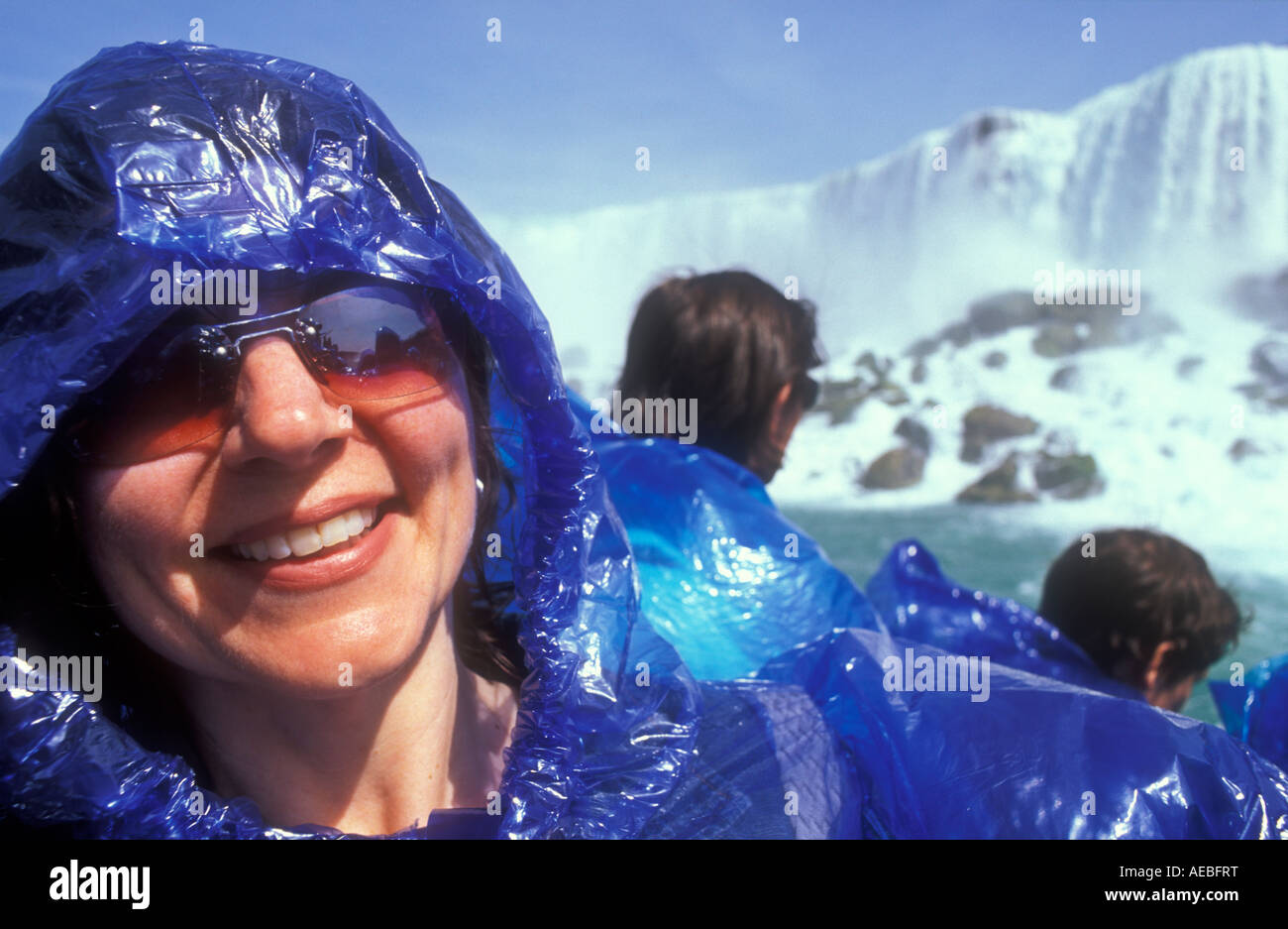 Canada Ontario Cascate del Niagara donna sorridente a bordo la Domestica della Foschia tour in barca con cascate Americane in background Foto Stock