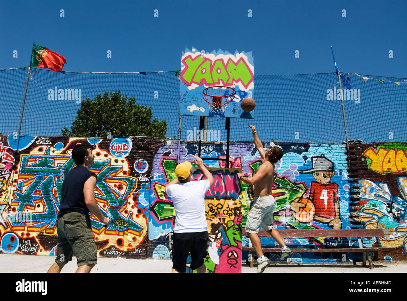 Campo da pallacanestro e giocatori accanto al coperto di graffiti muro di Berlino a East Side Gallery Berlin Foto Stock
