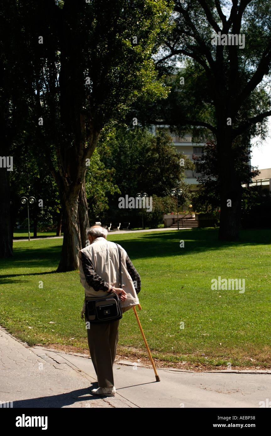 Il vecchio uomo a camminare in un parco su un luminoso giorno di estate Foto Stock