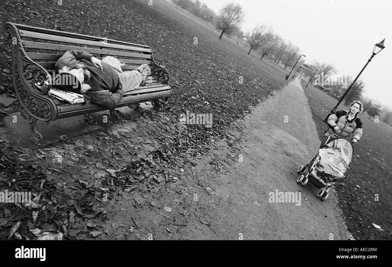 Un barbone dorme su un banco di lavoro su Clapham Common a Londra Giugno 2005 Foto Stock