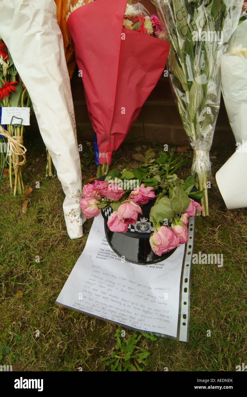 Un poliziotto del casco, omaggi floreali e un tributo scritta da uno dei suoi colleghi a sinistra in prossimità di un incidente mortale Foto Stock