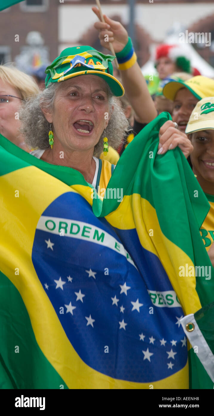 Un anziano brasiliano femmina tifoso tenendo un banner brasiliano cantando il suo inno nazionale Foto Stock