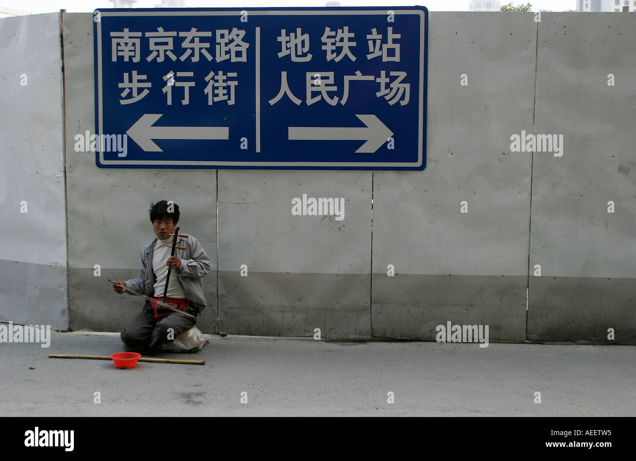 Shanghai in Cina un suonatore ambulante cieco svolge un tradizionale a due corde huquin cinese su un percorso temporaneo durante i lavori di costruzione Foto Stock