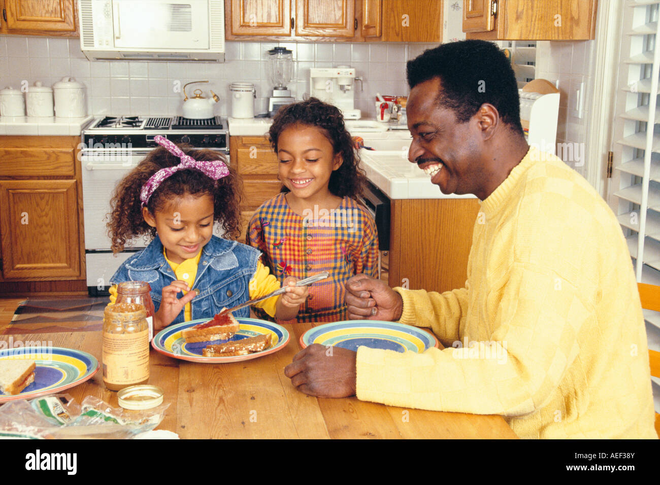 Papà e due figlie in cucina rendendo il pranzo multiculturale divertimento multi culturale della diversità razziale etnica etnicamente diversi MR ©Myrleen Pearson Foto Stock