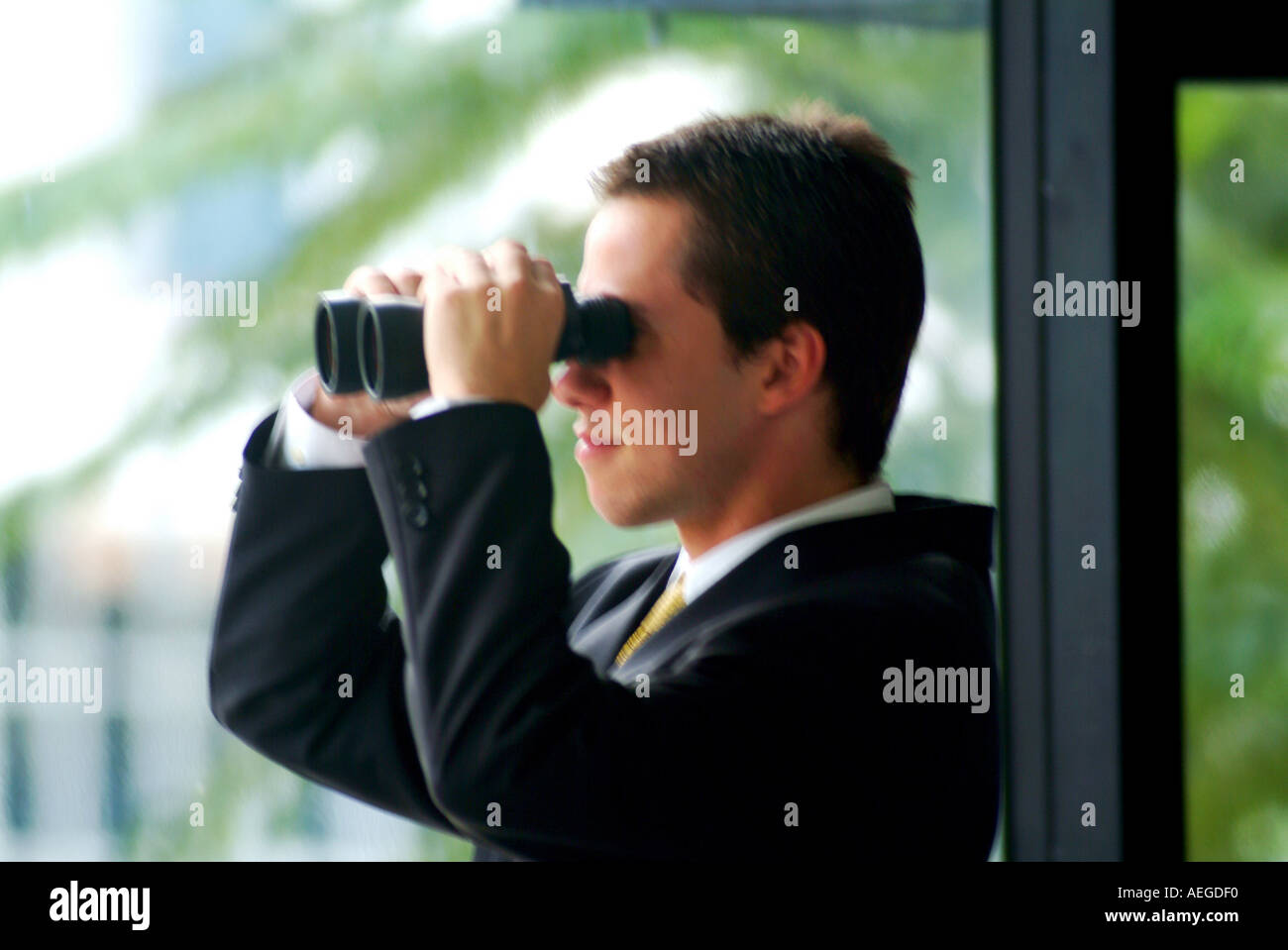 Imprenditore tuta in piedi tenendo il binocolo cercando guardando sbirciando curioso facendo leva fuori finestra futuro concettuale persone pe maschio Foto Stock