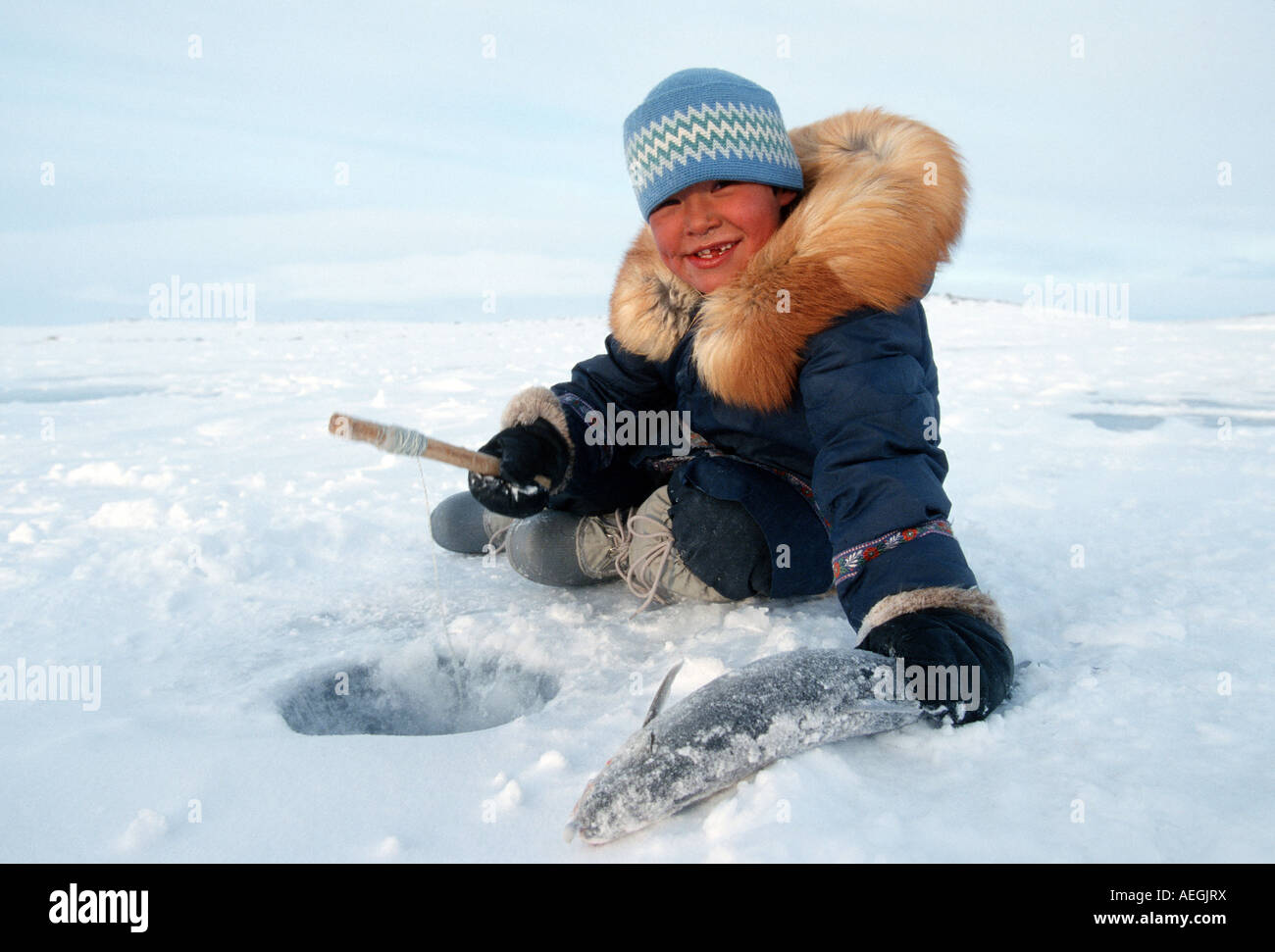 Inuit ragazzo di pesca in un foro ricavato su di un lago in Nunavik, Provincia di Quebec, Canada del Nord Foto Stock