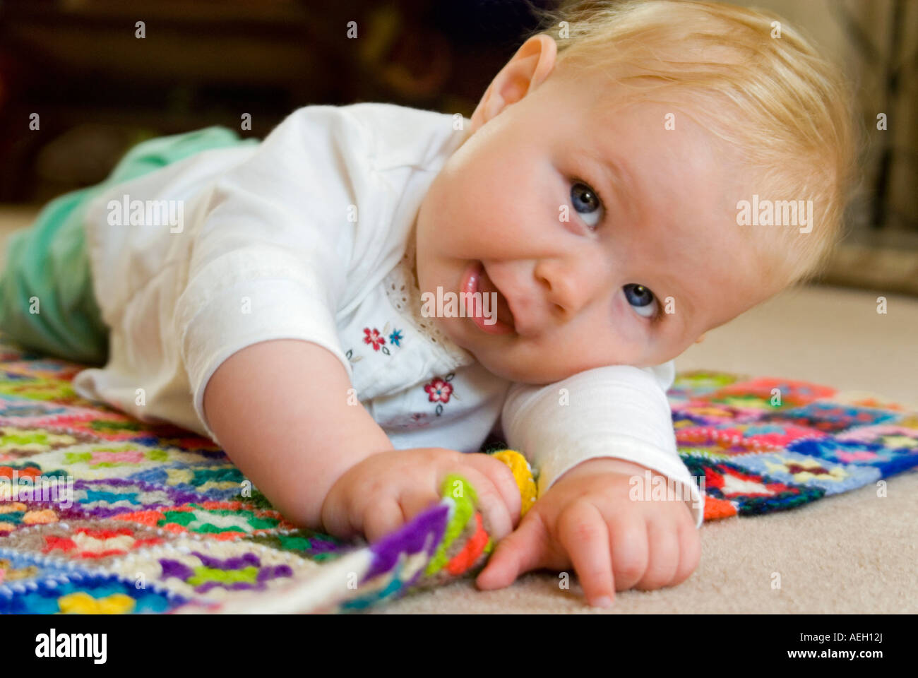 Chiudere orizzontale su ritratto di un periodo di sei mesi di età caucasian Baby girl rotolando sul pavimento Foto Stock