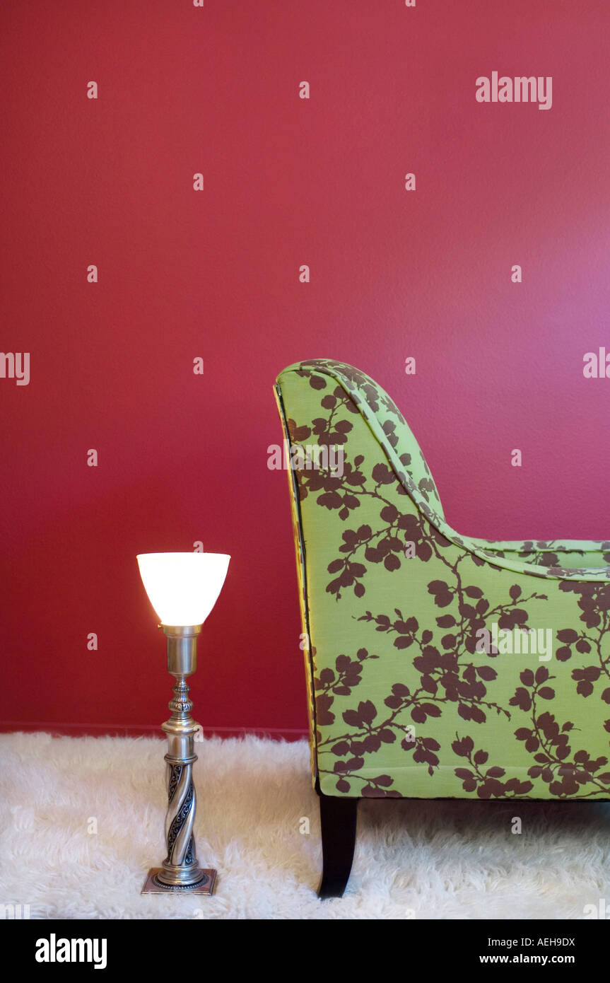 Tappeto di lana bianca di agnello su una parete rossa lampone e sedia in tessuto con tappezzeria verde lime floreale e lampada d'argento vintage. Foto Stock