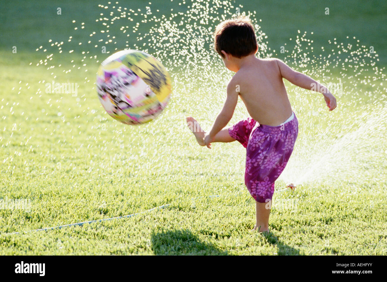 Ragazzo giocando a calcio in giardino Foto Stock