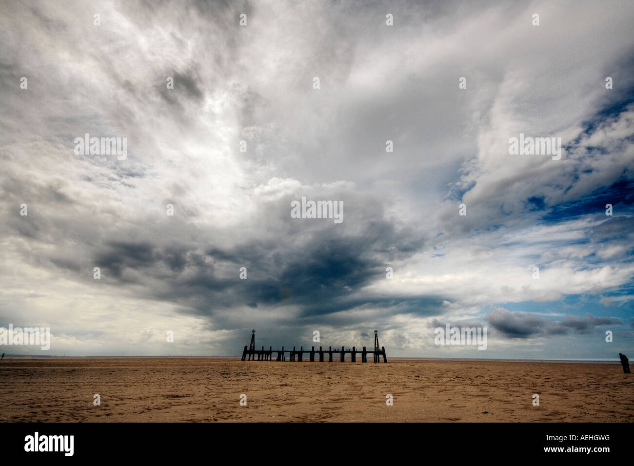 Lone figura camminare verso il molo vecchio a St Annes vicino al Blackpool costa di Fylde Nord Ovest Foto Stock