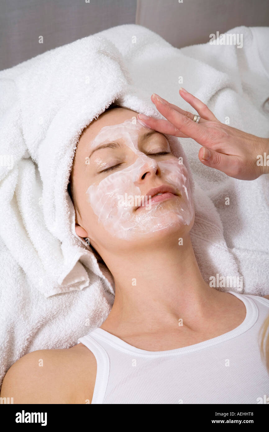 Cosmetico di applicare la maschera per il viso per la giovane donna e la faccia a vista in elevazione Foto Stock