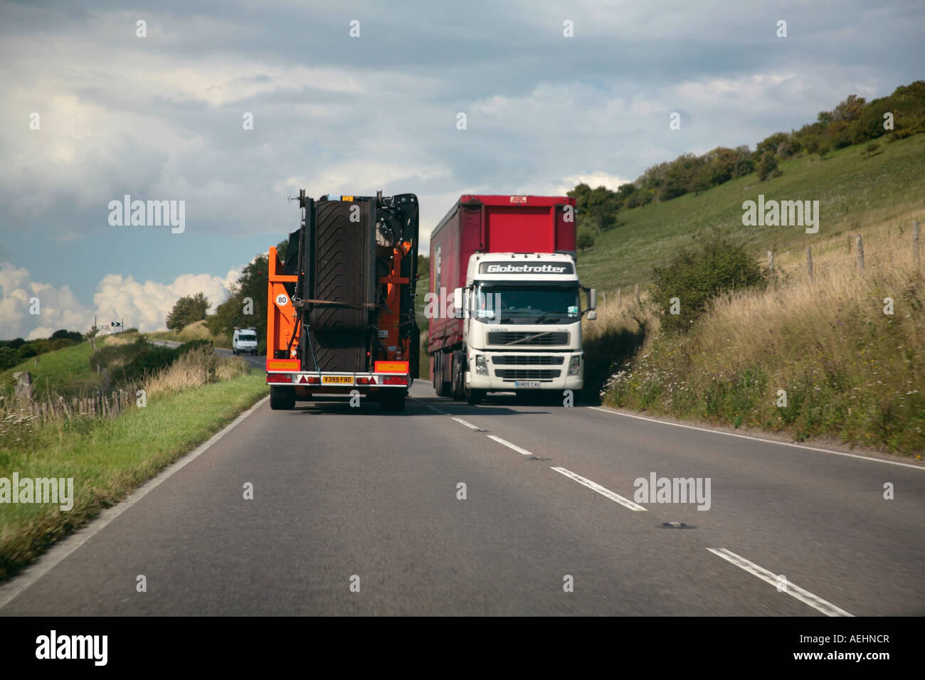 Due grandi autoveicoli pesanti adibiti al trasporto di merci in transito su una stretta English country road Foto Stock