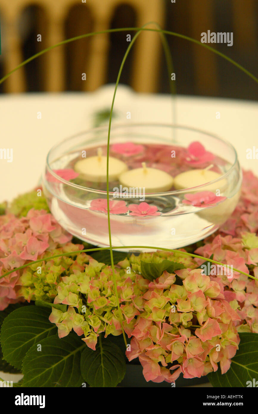 Centro di nozze-pezzo decorazioni per la tavola di candele galleggianti in  acqua in un recipiente in vetro con una base di fiori Foto stock - Alamy