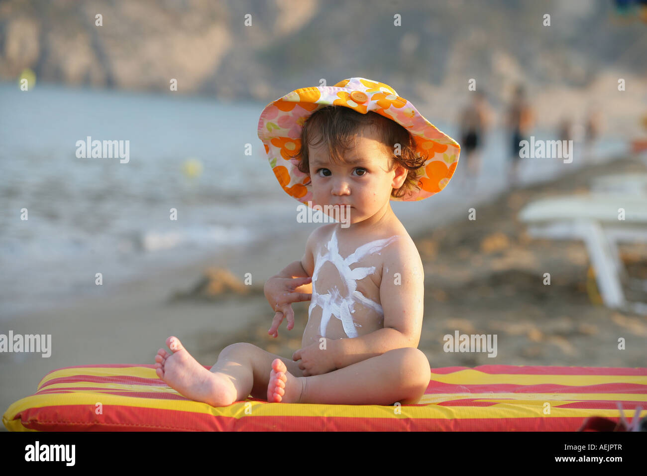 Bambino con lozione solare e parasole Foto Stock