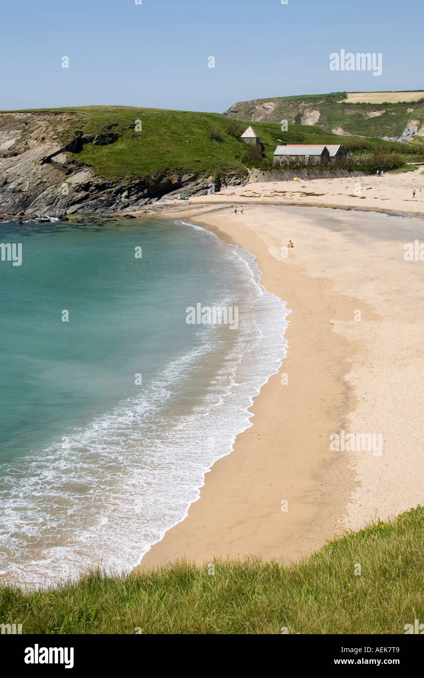Estate giorno paesaggio tranquillo mare turchese lambendo sulla spiaggia di sabbia Cornovaglia a Church Cove Gunwalloe con Chiesa di Saint Winwaloe oltre Inghilterra UK Foto Stock