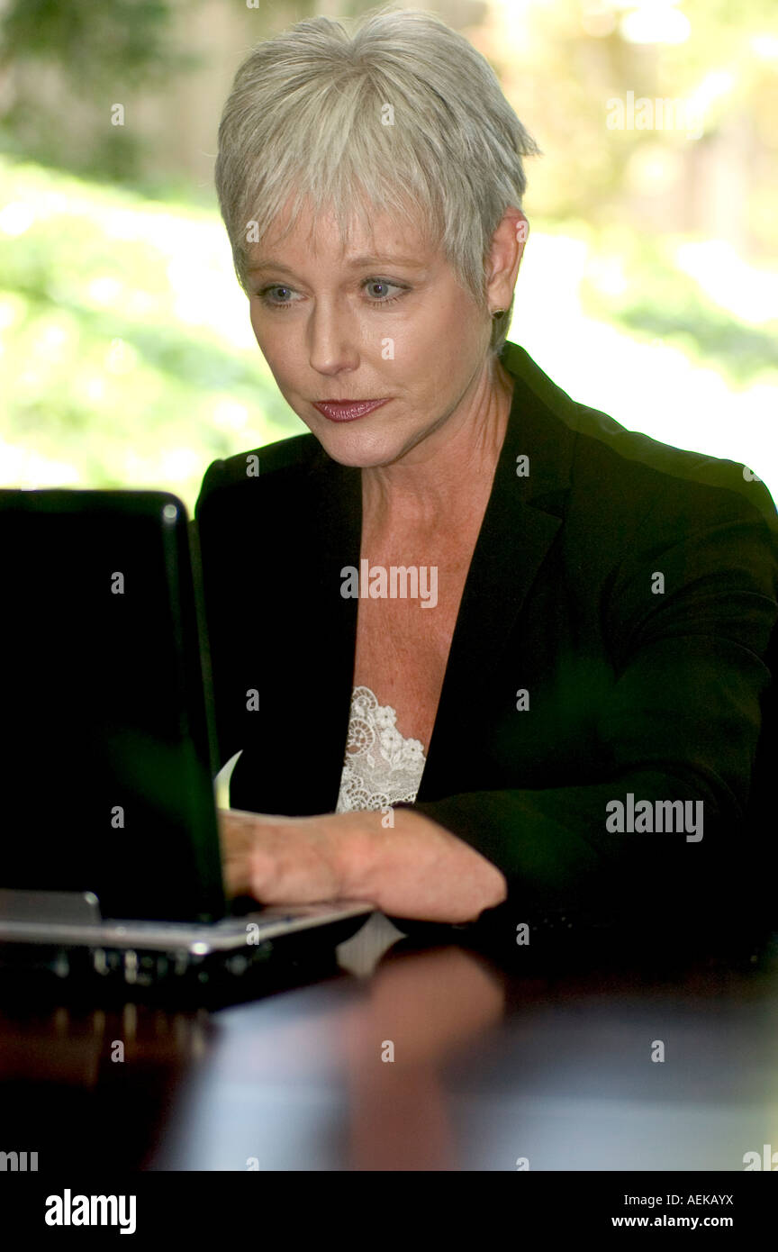 Donna matura in un business suit davanti a un computer portatile Foto Stock