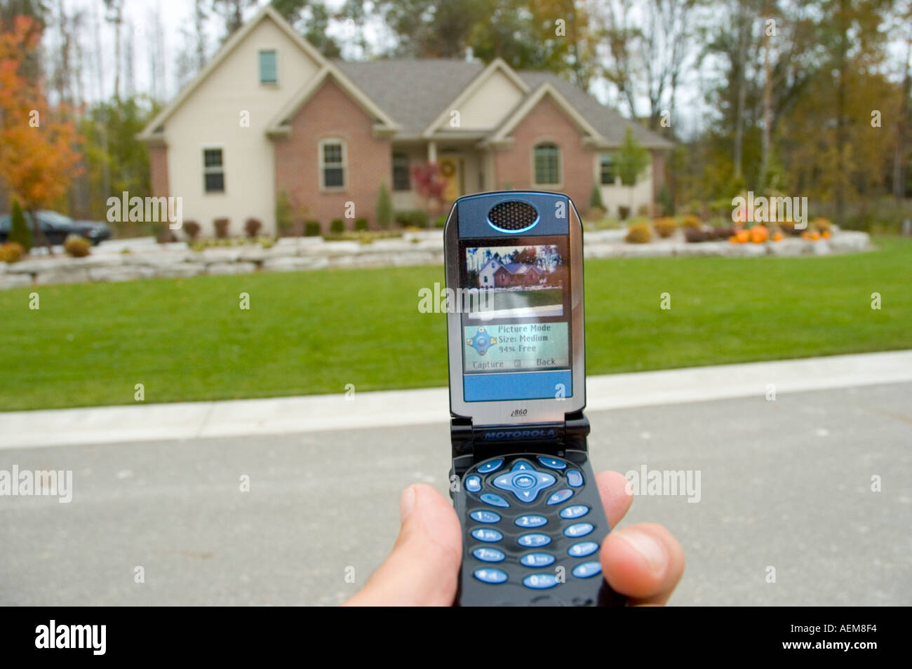 Il telefono cellulare è utilizzato per scattare una foto di una casa residenziale da un agente immobiliare Foto Stock