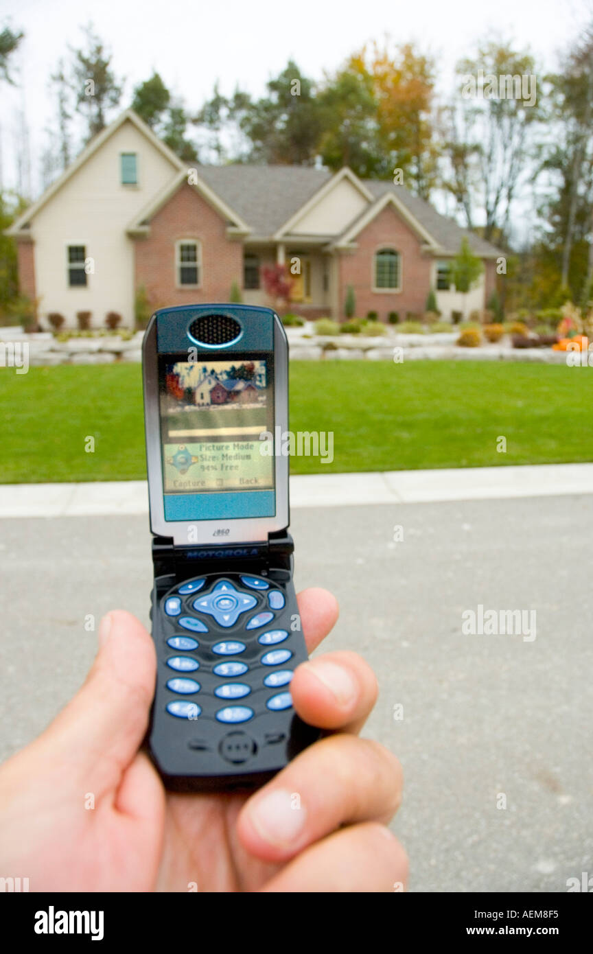 Il telefono cellulare è utilizzato per scattare una foto di una casa residenziale da un agente immobiliare Foto Stock