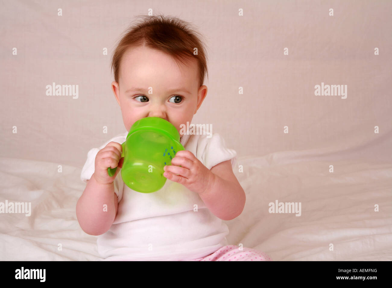 Giovane bambino neonato 7 mesi di bere dalla verde lime allattamento cup  Flacone Bicchiere mug mostra avanzate competenze di motore Foto stock -  Alamy