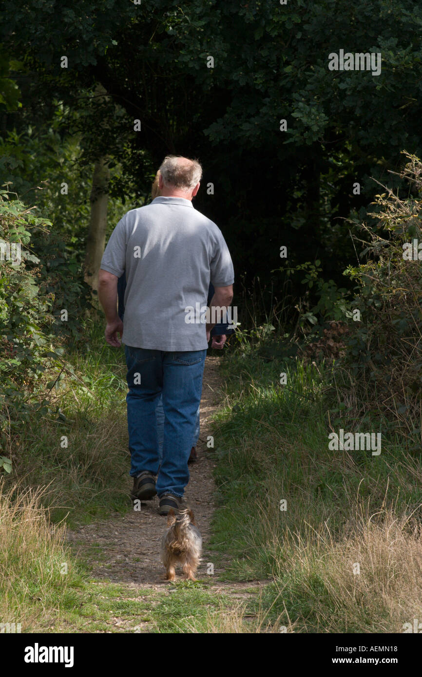 Un uomo di mezza età cammina il suo cane lungo una tranquilla strada di campagna tra Mogliano Veneto e Colchester Foto Stock