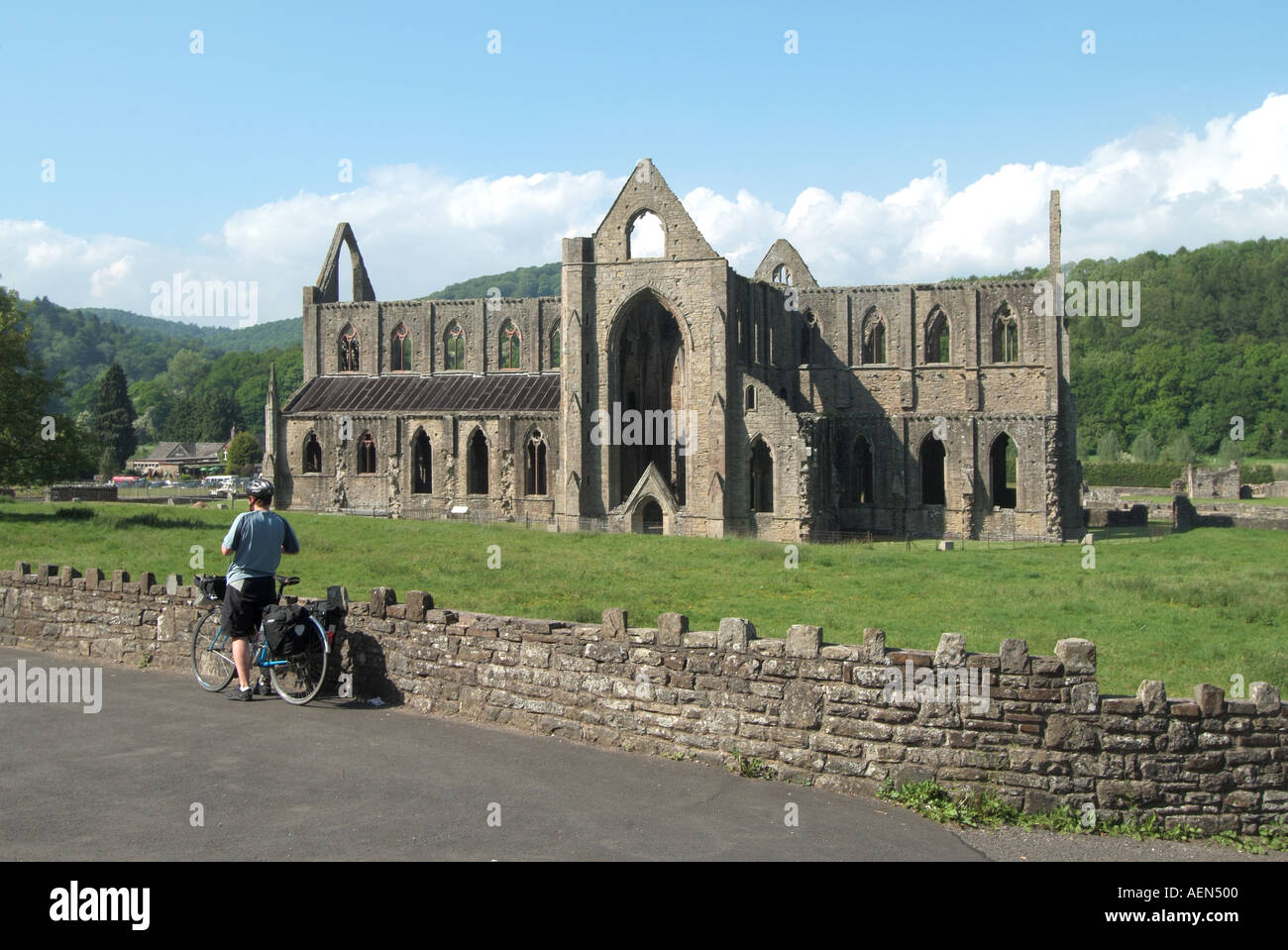 Tintern Abbey rovine del monastero nella valle del Wye, il Welsh banca del fiume Wye Monmouthshire Wales UK con ciclista ammirando la vista Foto Stock