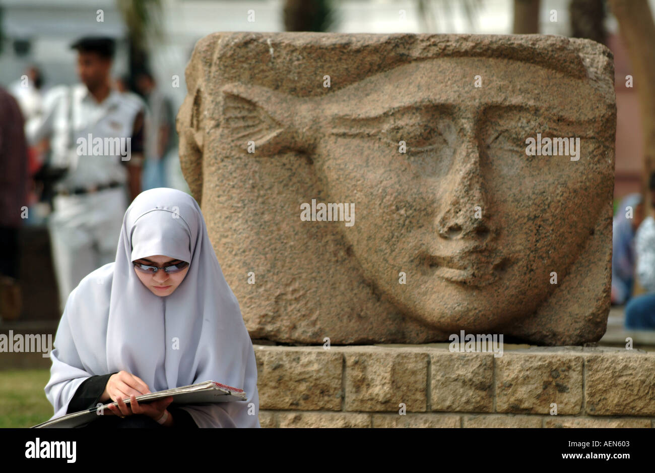 Donna musulmana seduta accanto alla antica Scultura egiziana museo del Cairo Foto Stock