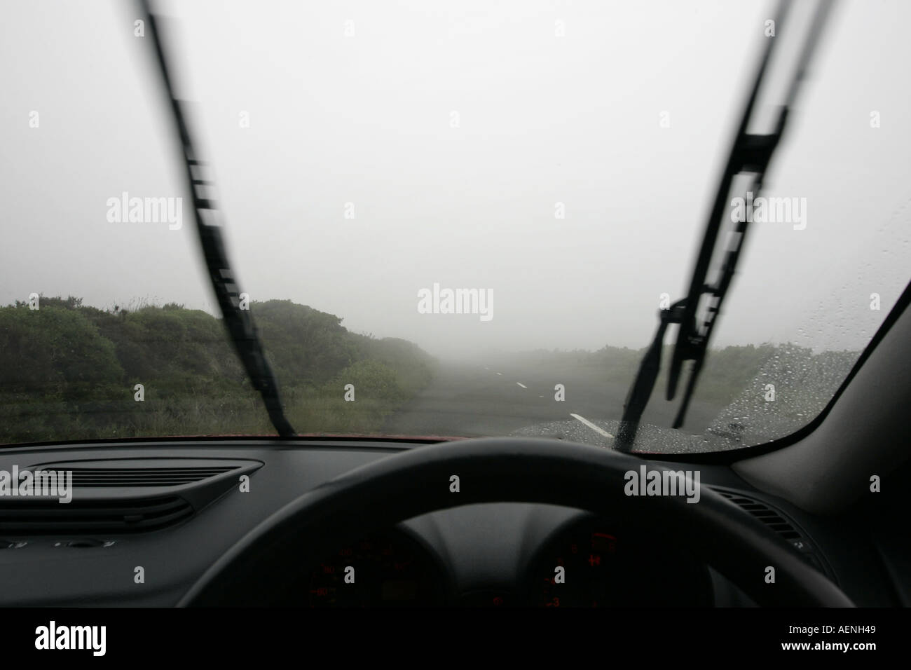 Tergivetri del parabrezza a lavorare sulla vettura voce paese lungo la strada di montagna è avvolta nella nebbia nebbia IOM Foto Stock