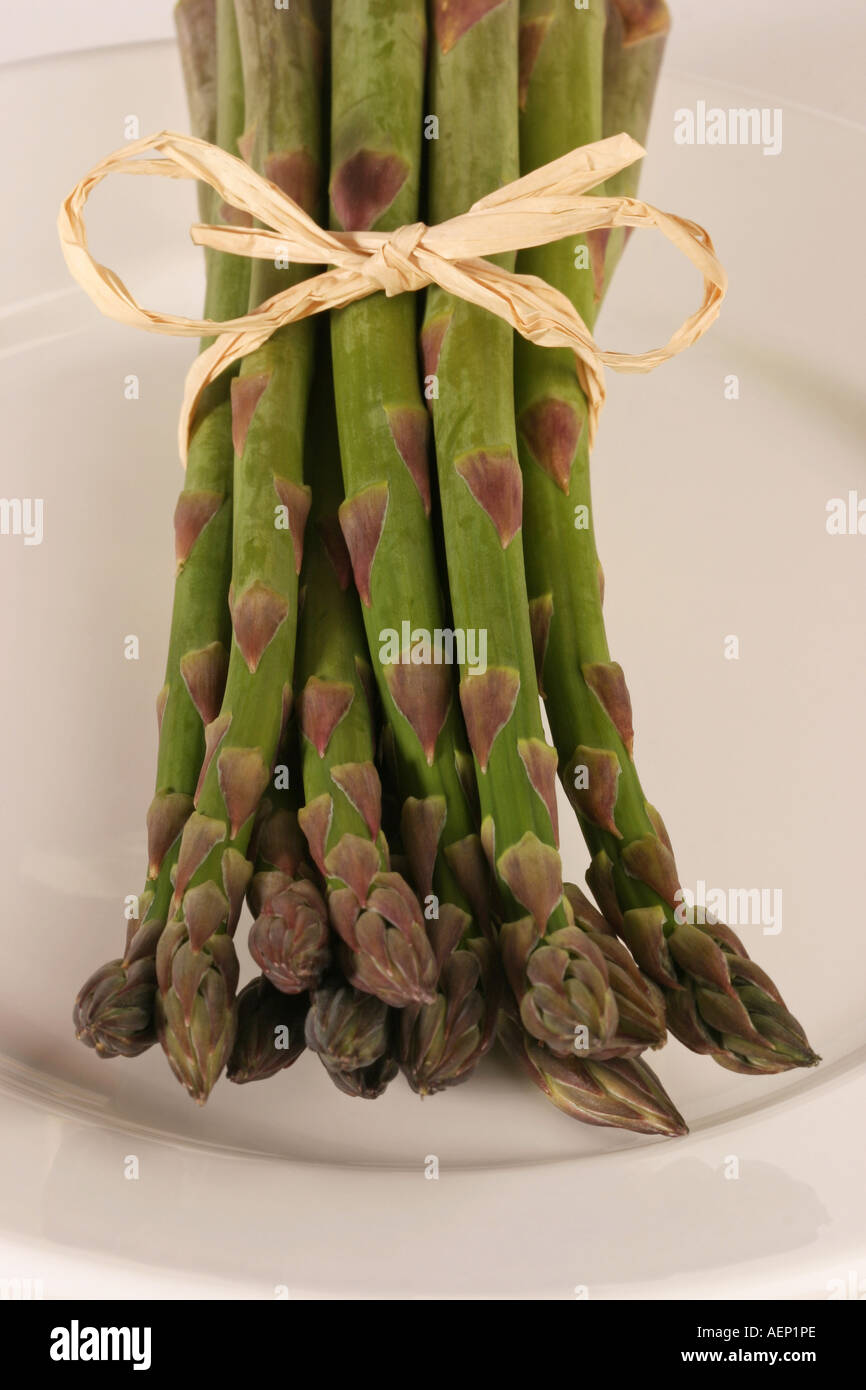 Gli asparagi spears su una piastra bianca legata con rafia Foto Stock