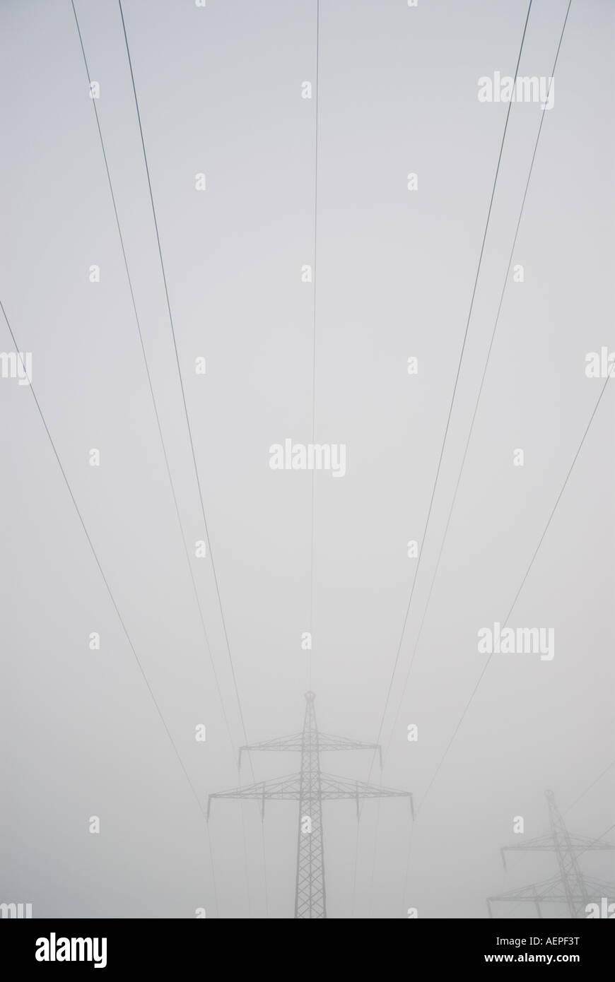 Le linee elettriche svaniscono nella fitta nebbia Foto Stock