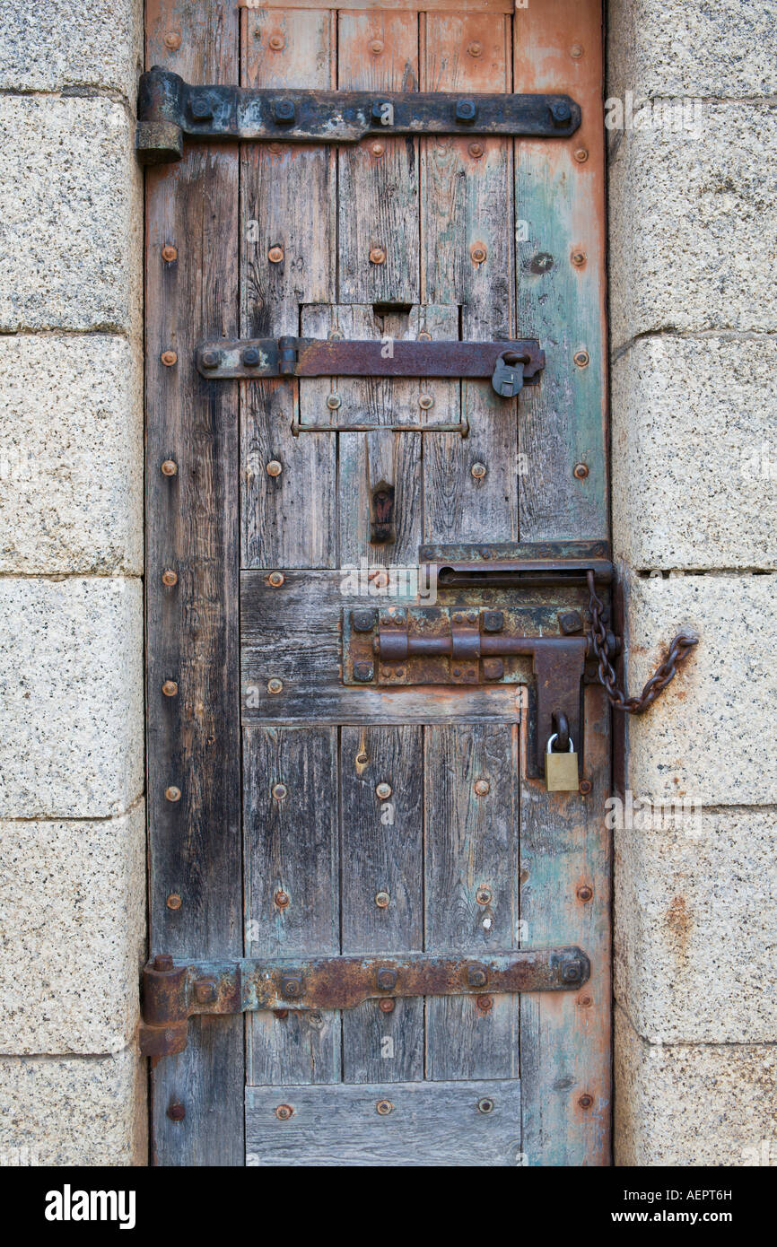 Vecchia porta di legno con cerniere, bullone e lucchetto, insieme alla luce dei blocchi di granito. Foto Stock