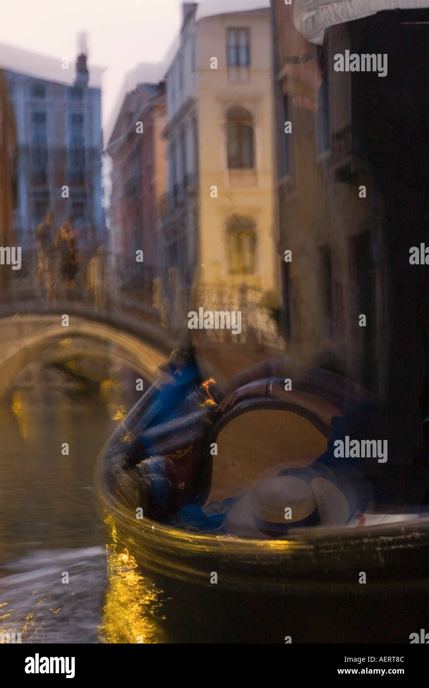 Giovane sorge sul ponte sul canal al crepuscolo con gondola in primo piano Venezia Italia Foto Stock